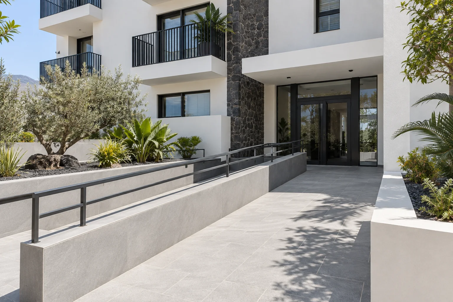 Recreación conceptual de un acceso residencial con fachada blanca, piedra gris y rampa.